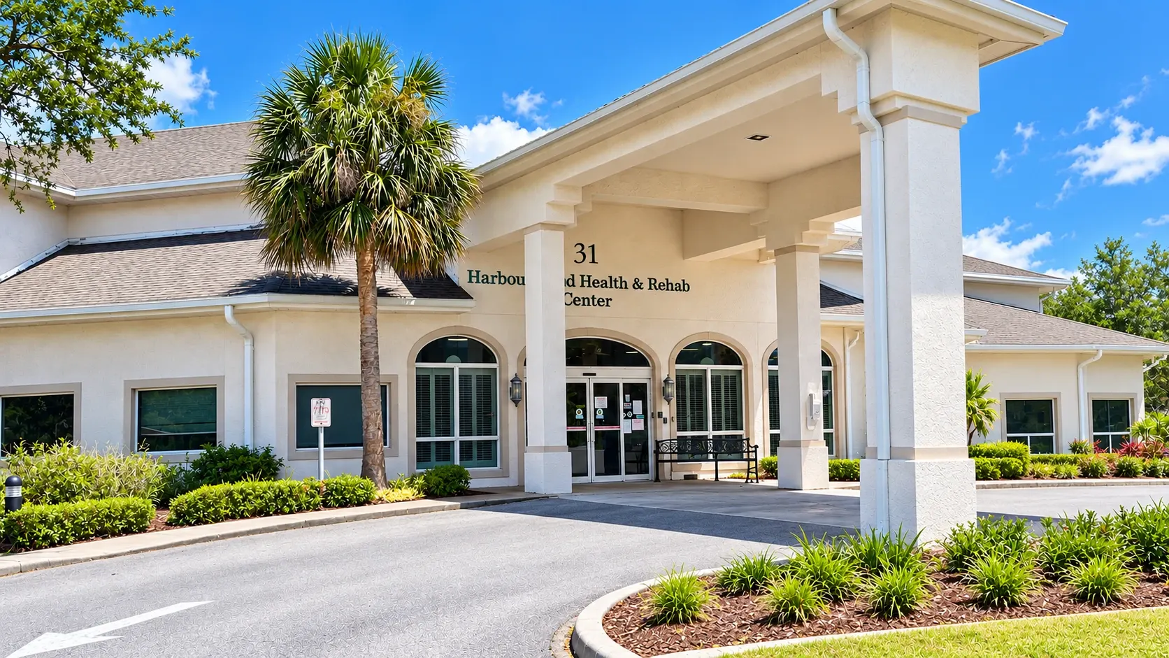 The covered entrance of Vivo Healthcare Harbourwood, under its palms